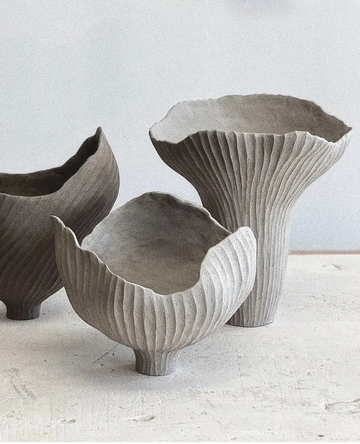 Three ceramic vases with a ribbed texture in neutral tones, arranged on a white surface against a plain background.