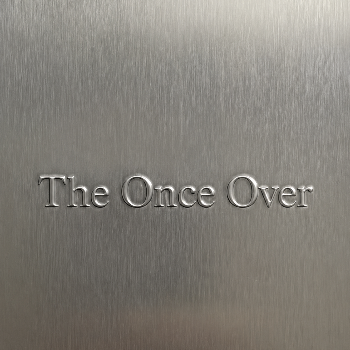 Text engraved on a metallic surface that reads 'The Once Over'.