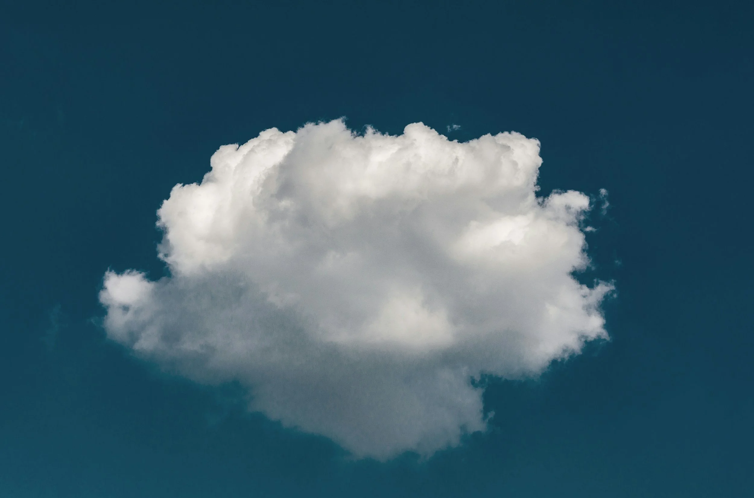 A white, fluffy cloud against a dark blue sky.