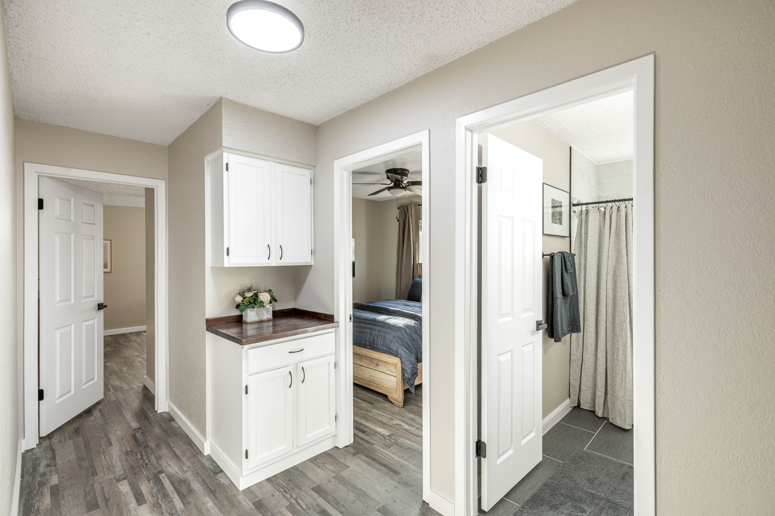 View of a hallway with multiple doors leading to bedrooms and bathrooms in a modern home interior.