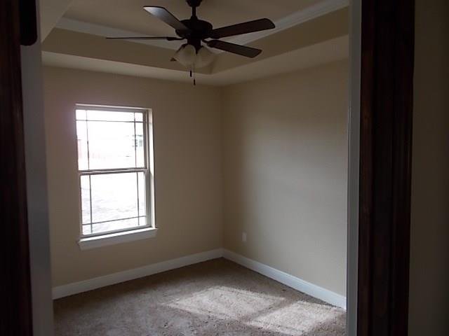 Empty beige bedroom with a window, ceiling fan, and carpeted floor.