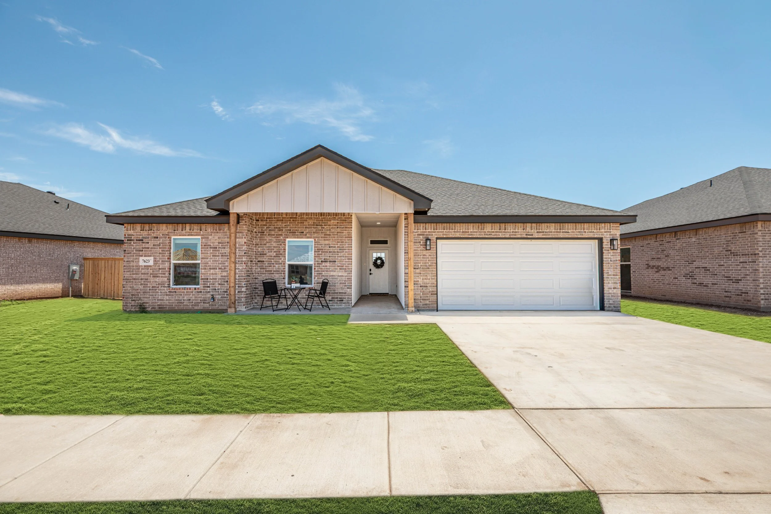 Newly built single-story house with a front yard, driveway, black and brick exterior, and a two-car garage.