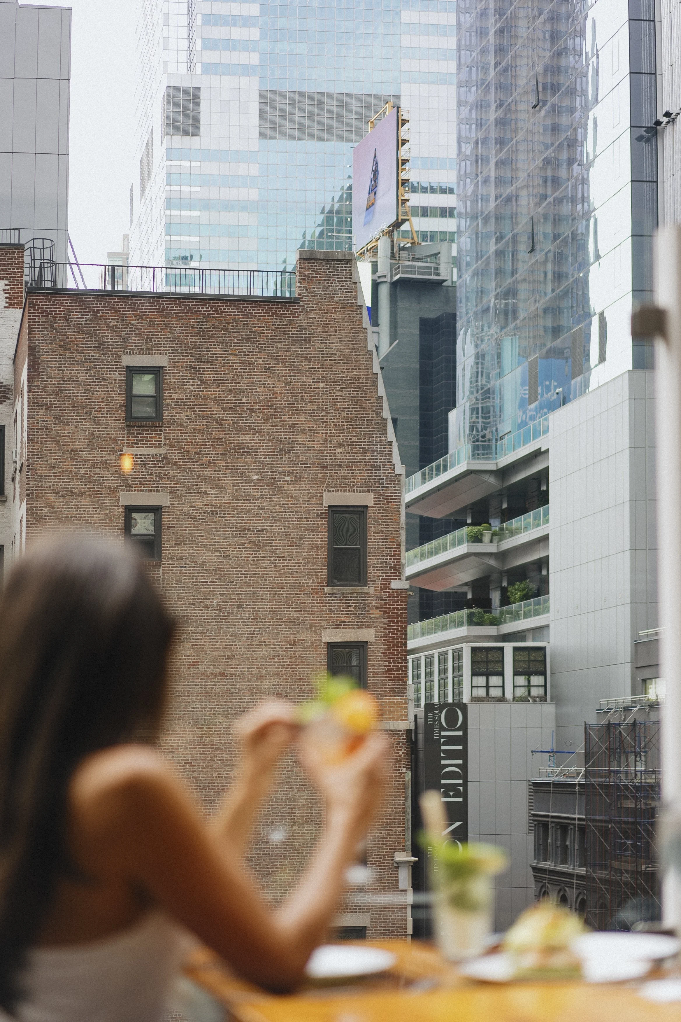 People enjoying a meal outdoors on a city rooftop with tall modern buildings in the background.