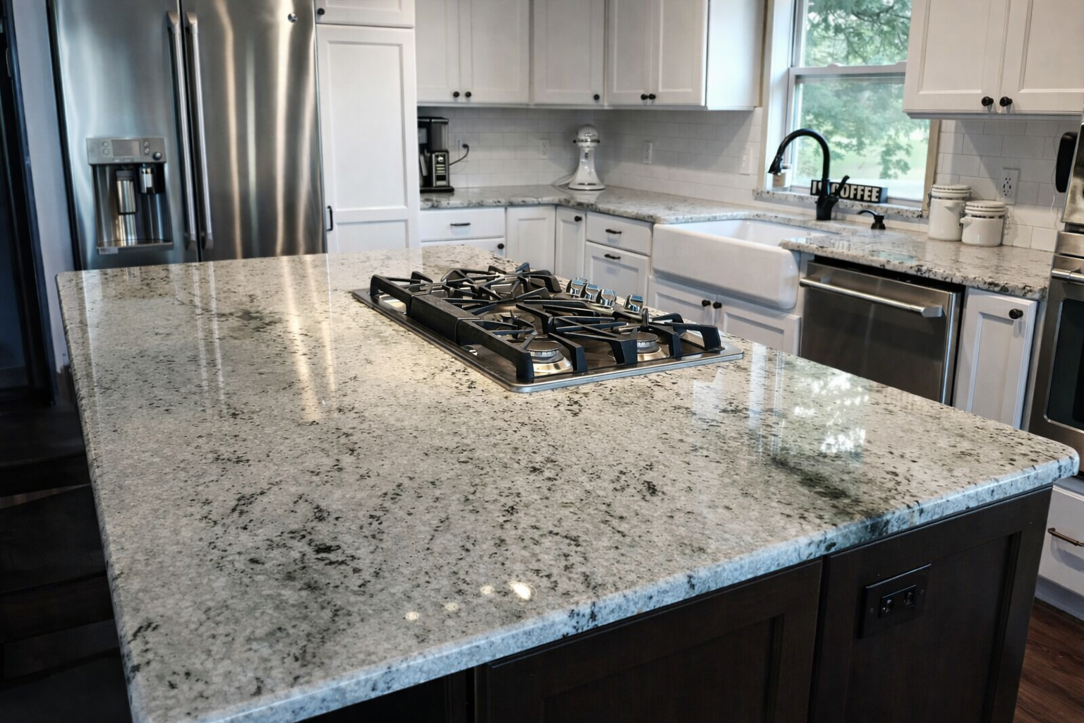Modern kitchen with granite countertops, stainless steel appliances, white cabinets, and a large kitchen island with a gas stove.