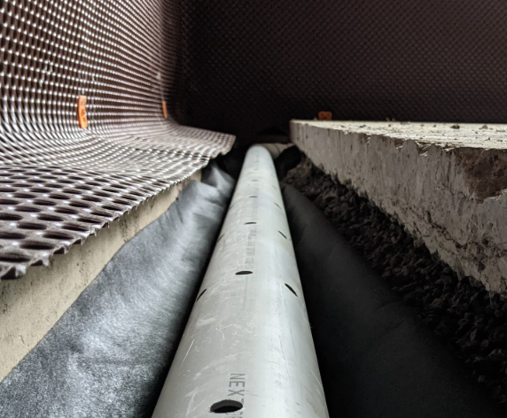 Close-up view of a large underground pipe installation, with construction materials surrounding it.