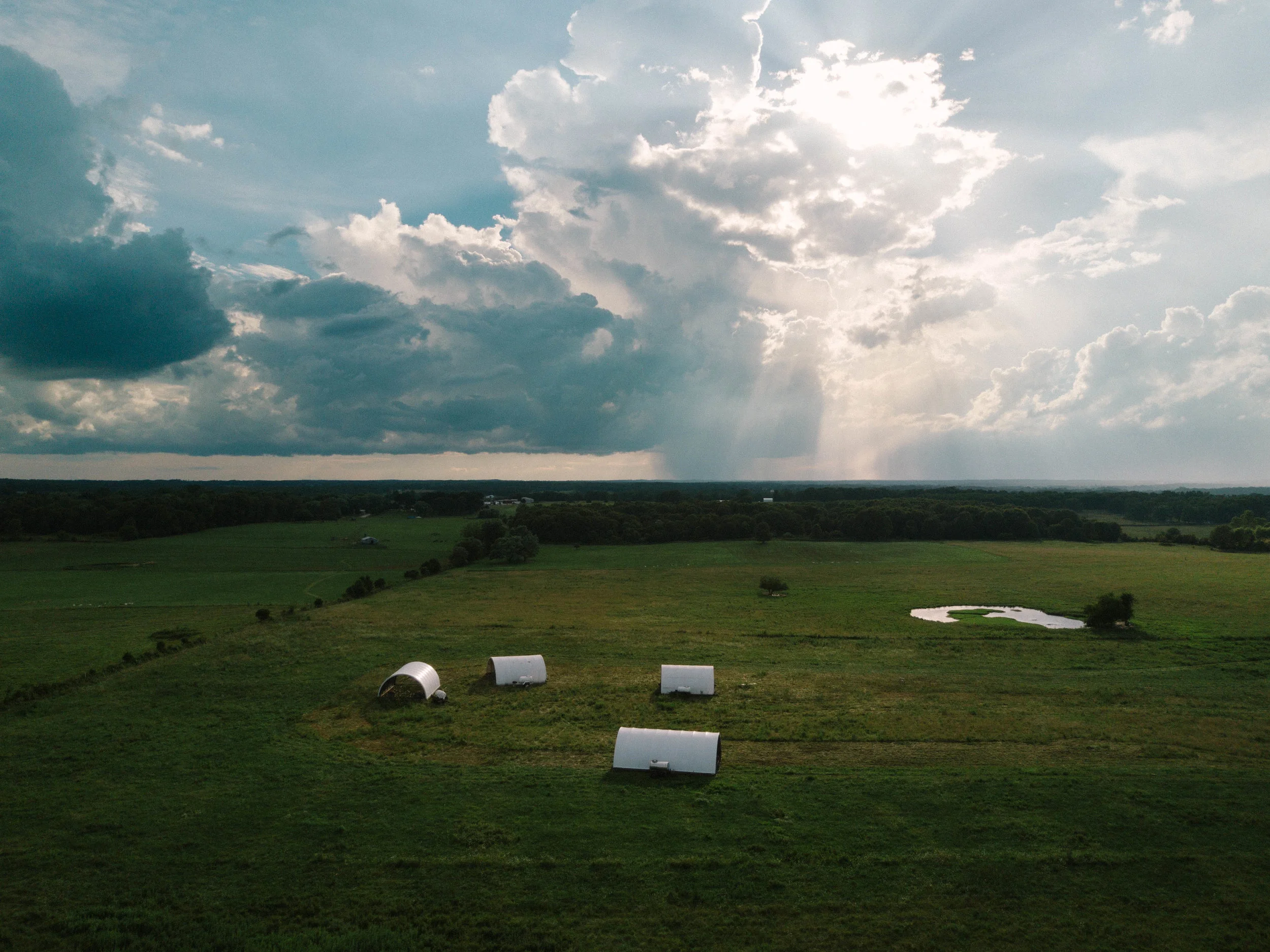 Chicken hoop houses under magnificent sky.