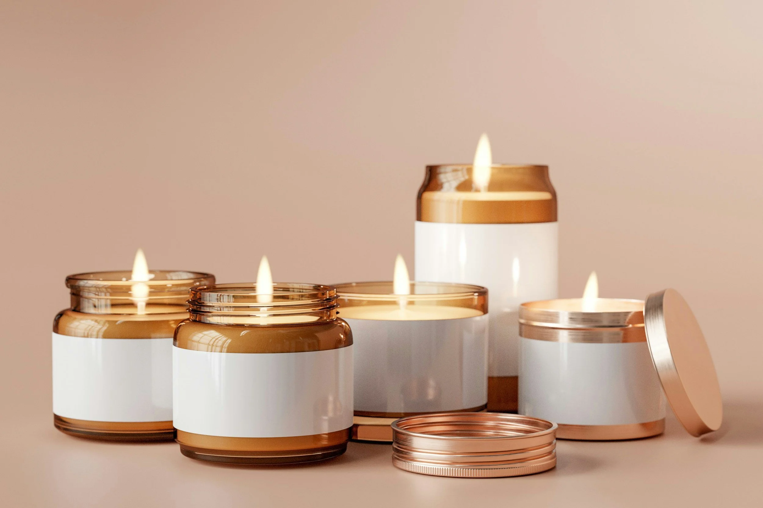 Several small candles in glass containers with metallic accents glowing against a beige background.