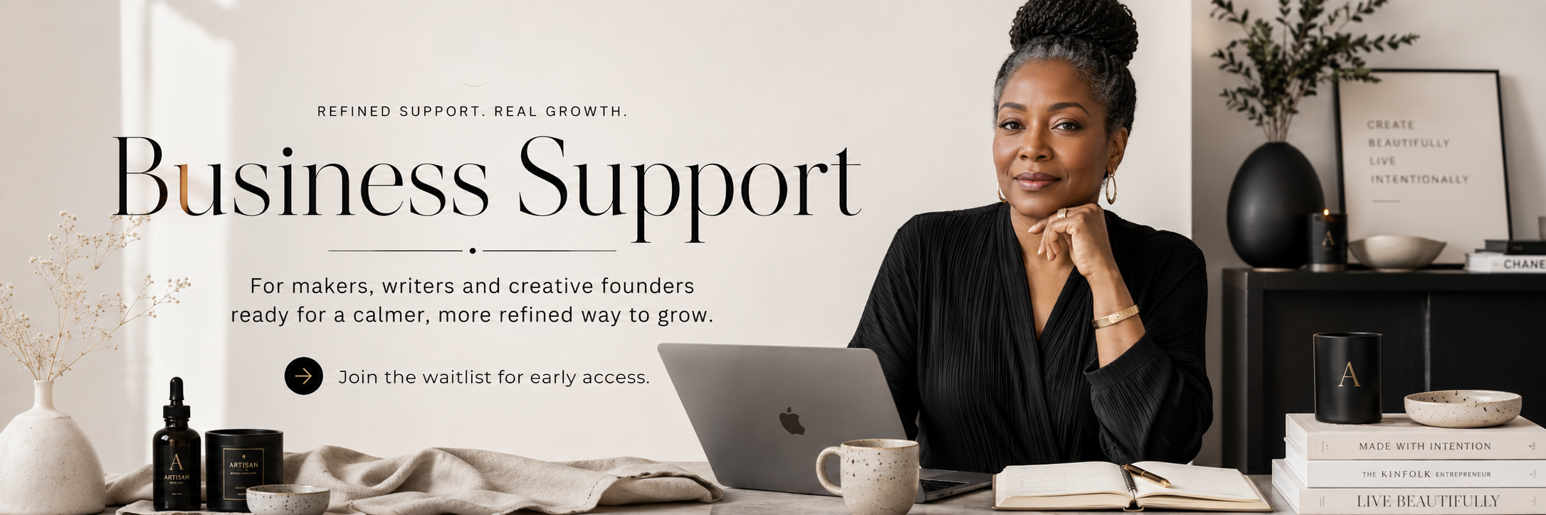 A woman sitting at a desk with a laptop, coffee mug, and books, in a stylish office setting promoting business support for creators and writers.