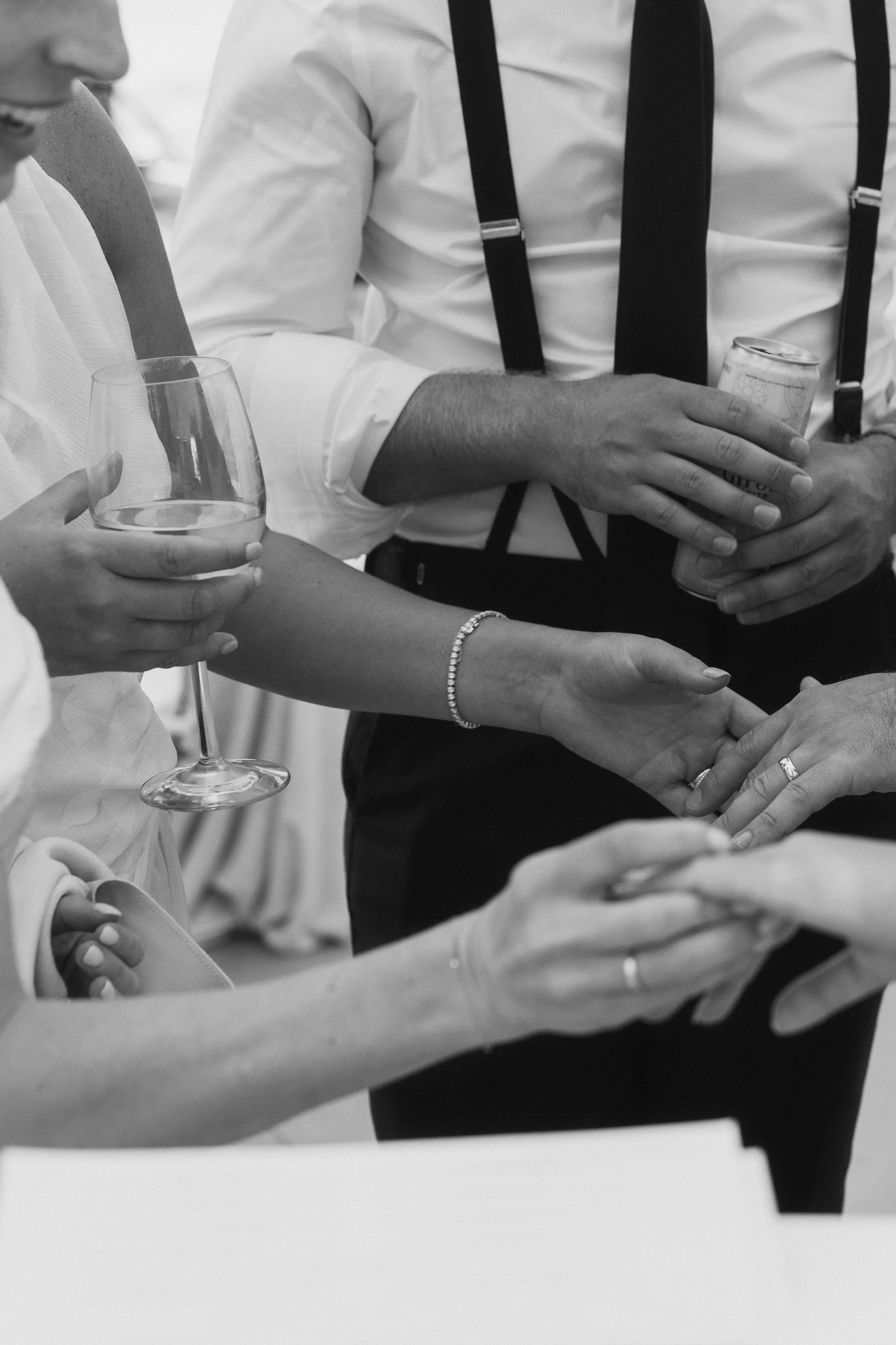 People holding hands and drinks at a social gathering.