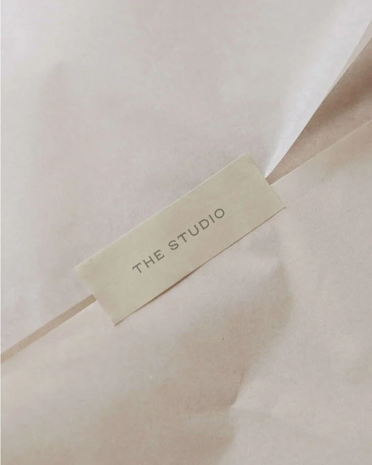 Close-up of a white paper or fabric with a small label reading "THE STUDIO" attached.