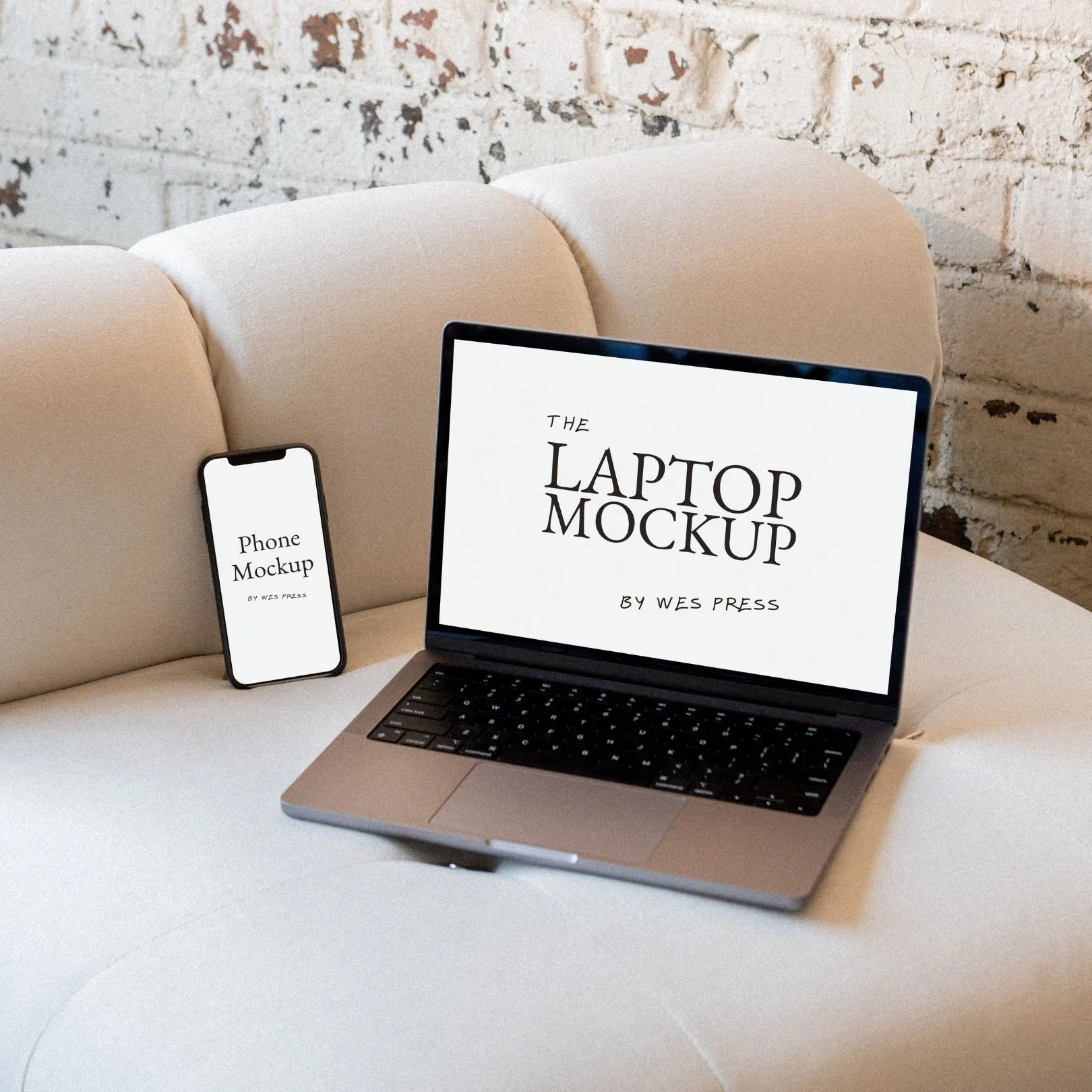 Laptop and phone on a white couch, with the laptop displaying 'The Laptop Mockup by Wes Press' and the phone showing 'Phone Mockup by Wes Press'