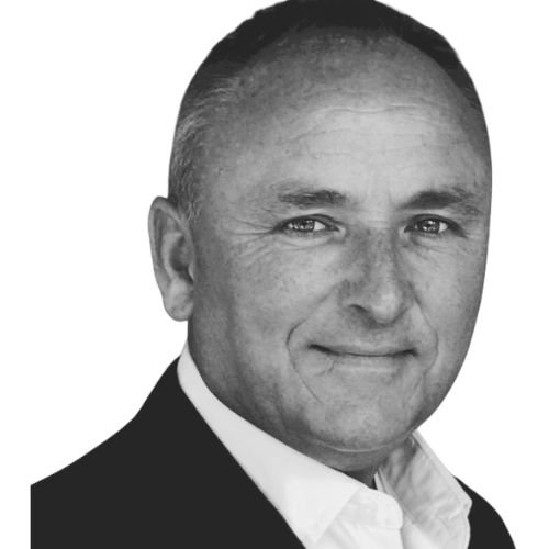 Black and white professional headshot of a man with short hair, wearing a suit and white shirt, smiling slightly.
