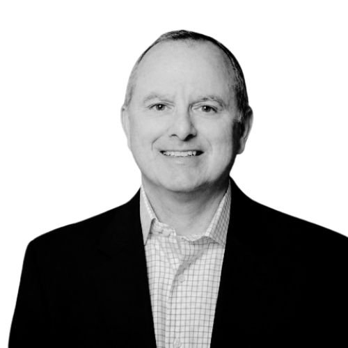 Black and white portrait of a smiling man in a suit and checkered shirt.