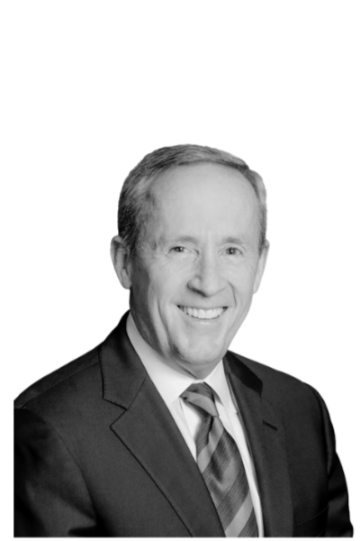 A black and white headshot of a smiling man in a suit and tie.