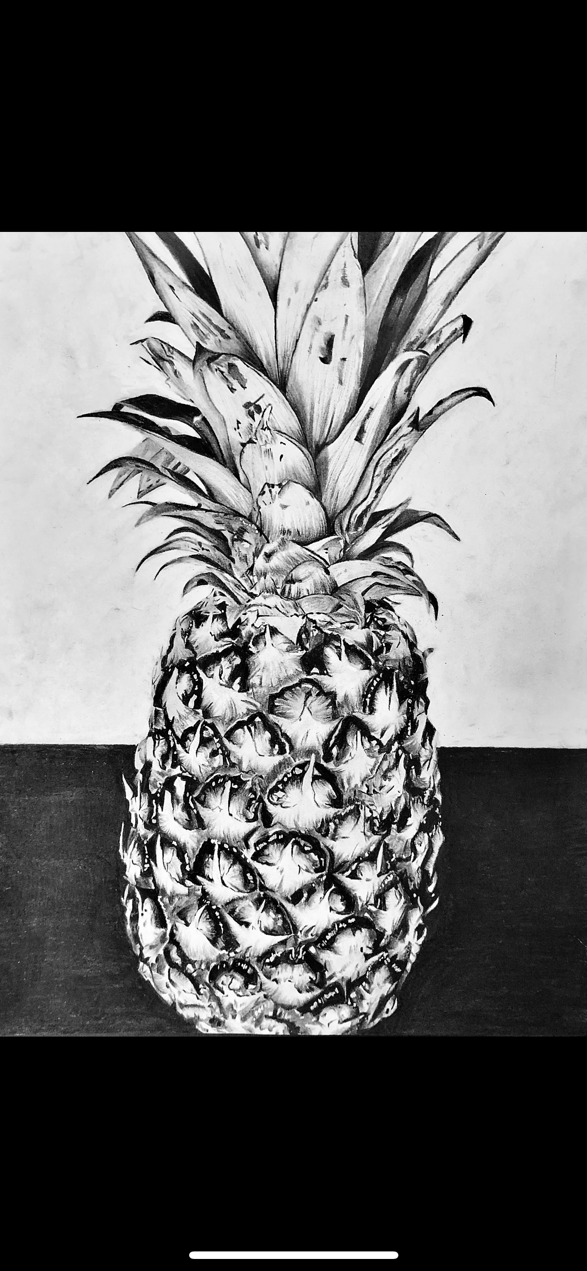 Black and white drawing of a pineapple with detailed texture and leaves, placed on a dark surface with a plain background.