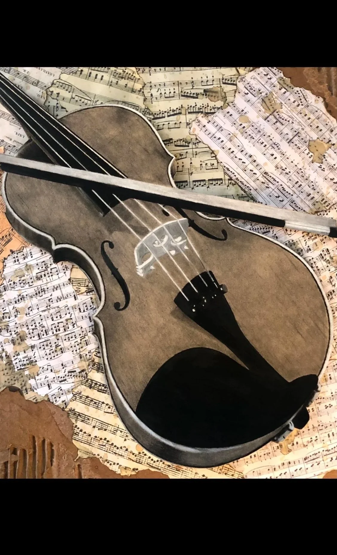 Close-up of a violin with a bow on top, surrounded by torn sheets of musical notes and sheet music.