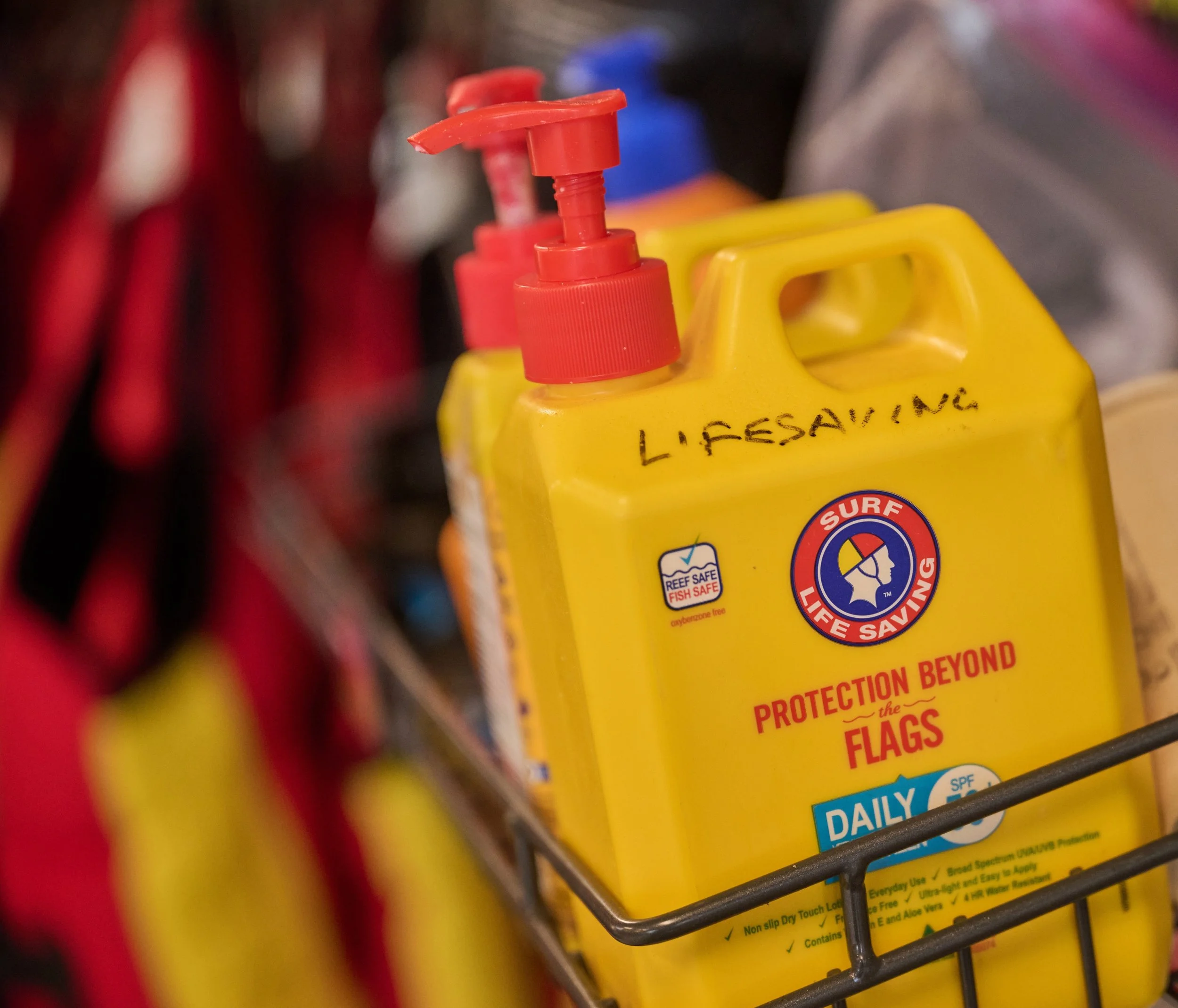 Close-up of large yellow bottles of sunscreen with red nozzles in a store, labeled with safety warnings