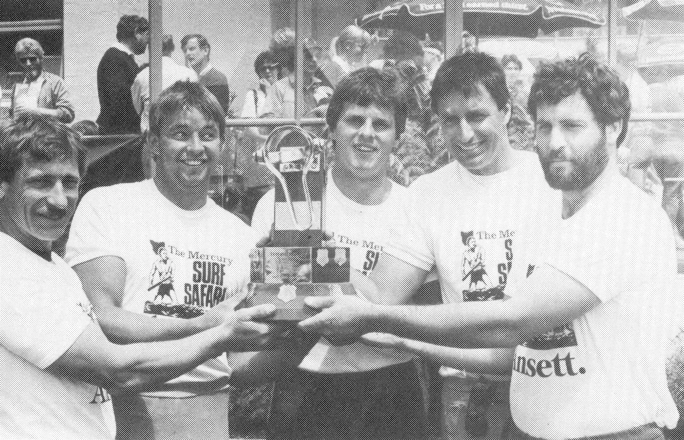 A group of young people celebrating with a trophy, smiling.