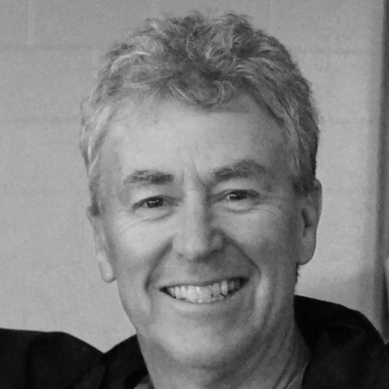 Black and white photo of a smiling middle-aged man with short, curly hair.