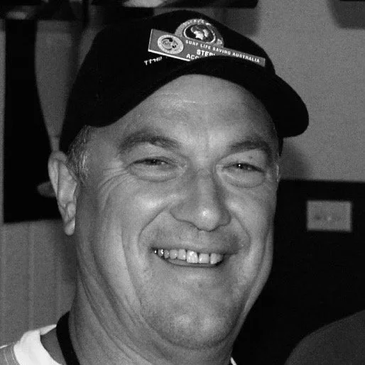 Man smiling wearing a cap with logos, in black and white.
