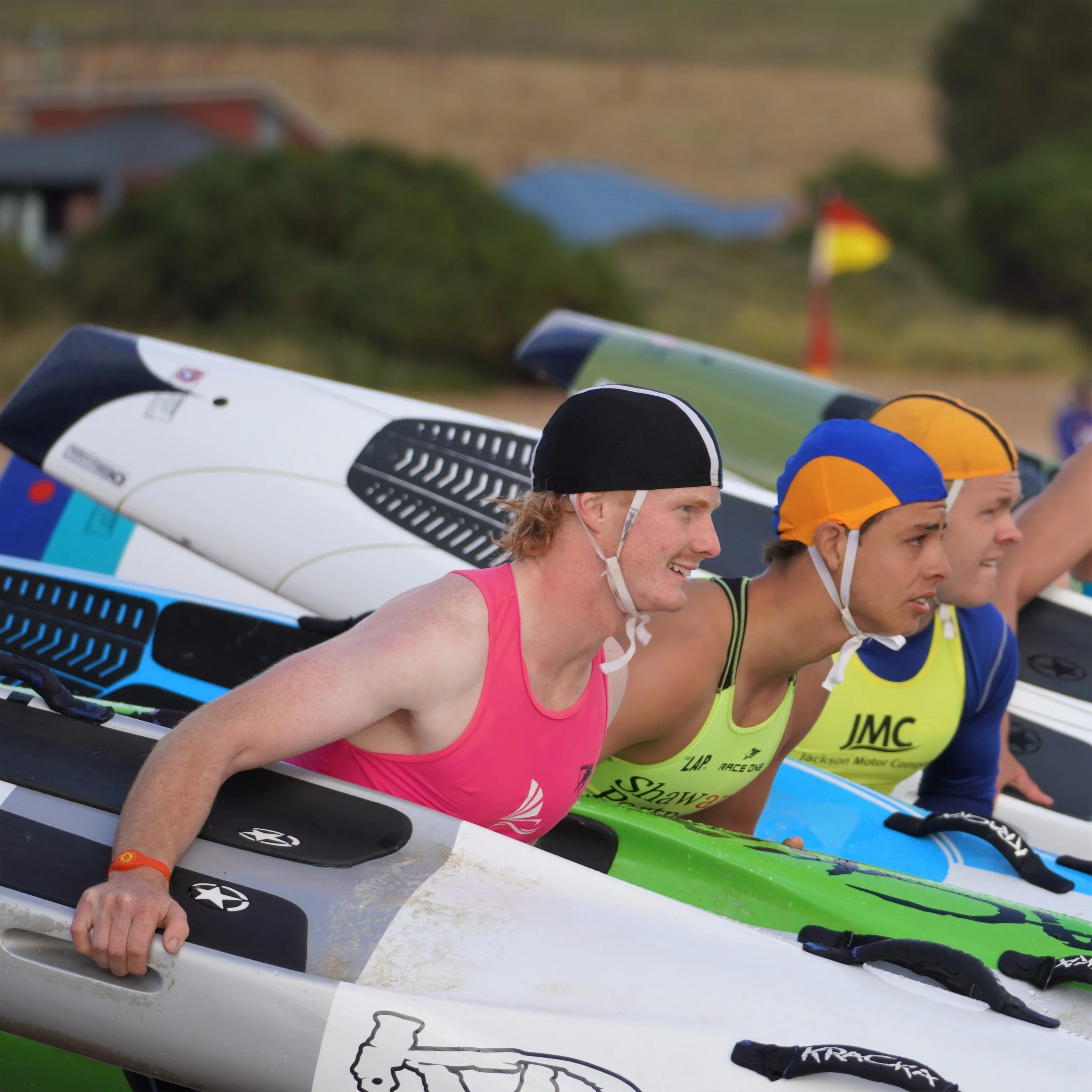 Group of people preparing for a kayaking race, holding their paddles and wearing helmets.