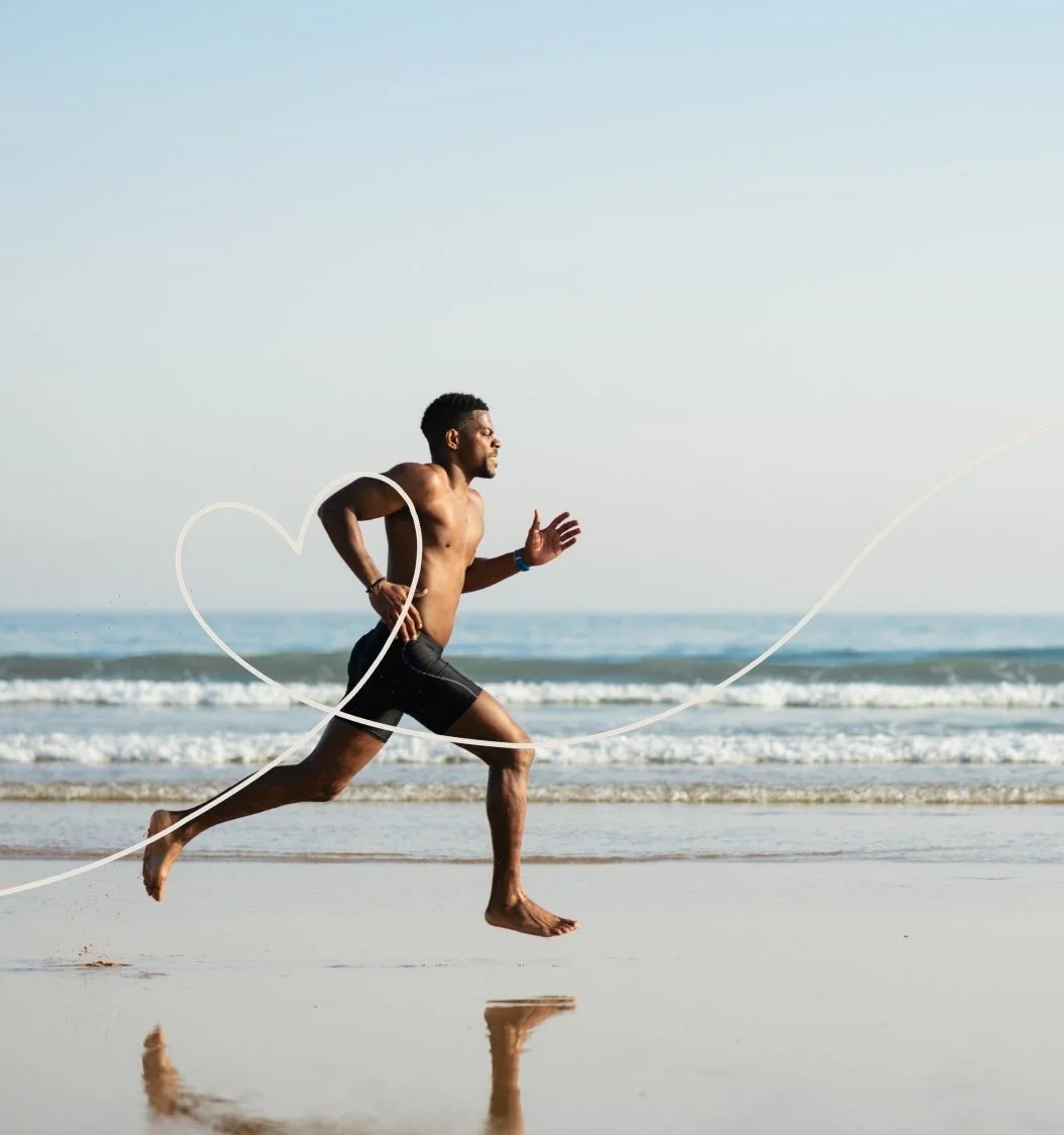 A man runs on the beach during daytime, with the ocean in the background and a heart-shaped graphic overlay.