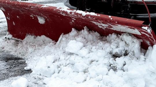 Snowplow clearing snow from a roadway during winter.