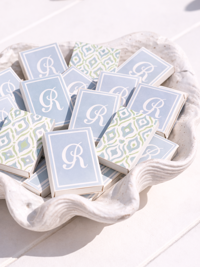 Small boxes with a light blue and white design, featuring a prominent white letter 'R', arranged in a white shell-shaped dish.