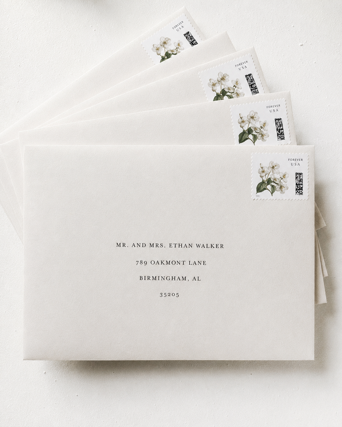 A set of white envelopes with floral postage stamps and address labels, arranged on a white surface.