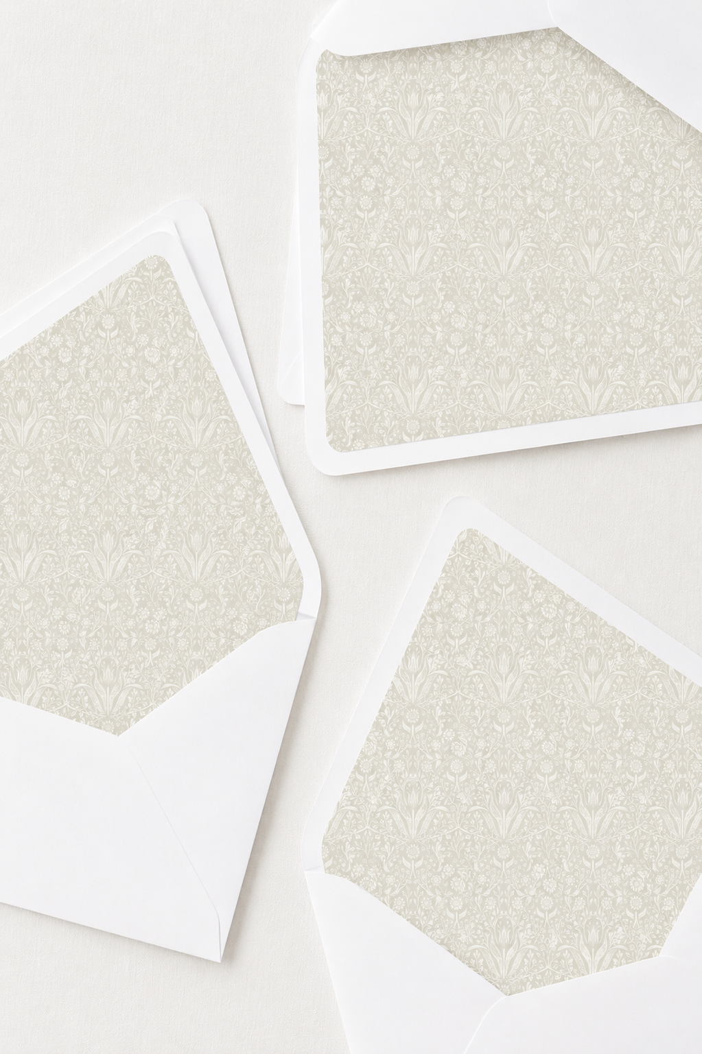 Three white envelopes with floral patterned lining inside, placed on a white surface.