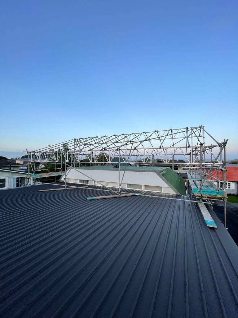 Metal scaffolding on rooftops with a clear evening sky in the background in Auckland.