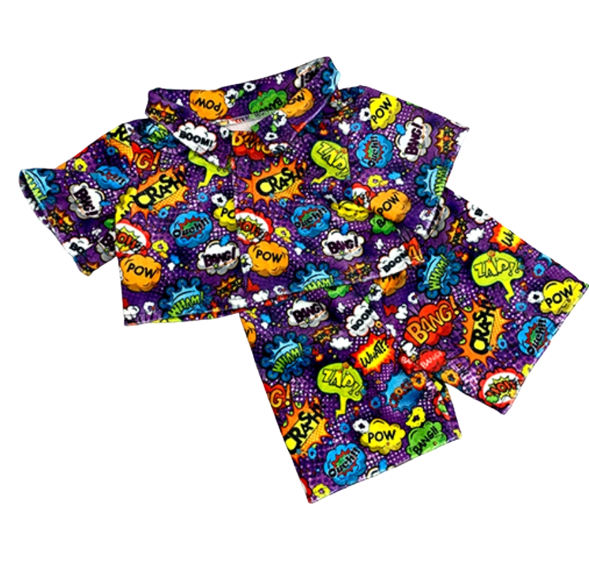Children's short-sleeve pajamas with a comic book print featuring words like 'POW,' 'BANG,' 'WOW,' 'ZAP,' and 'BOOM,' on a purple background.