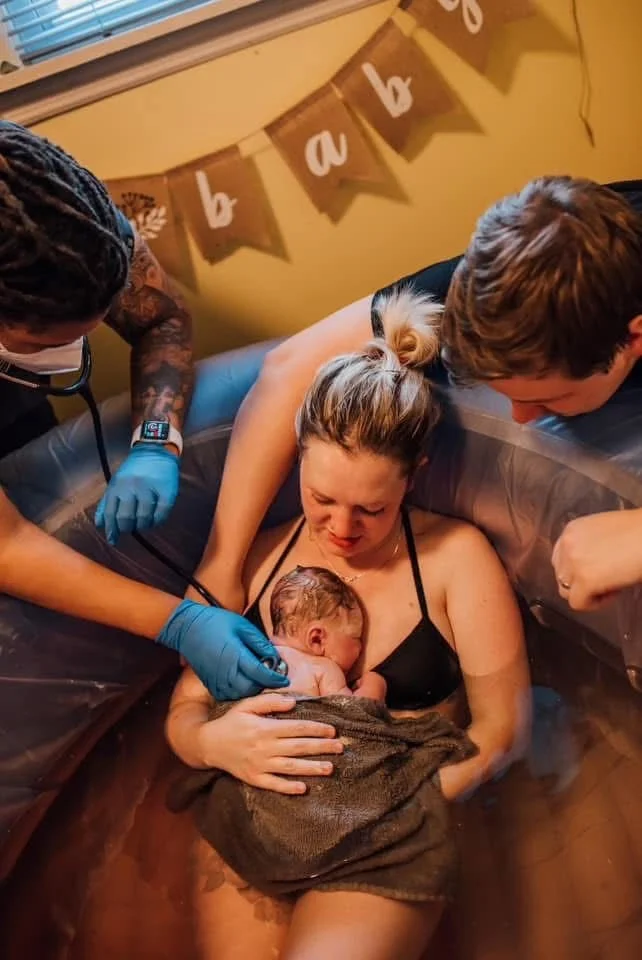 woman in birth tub holding baby skin to skin 