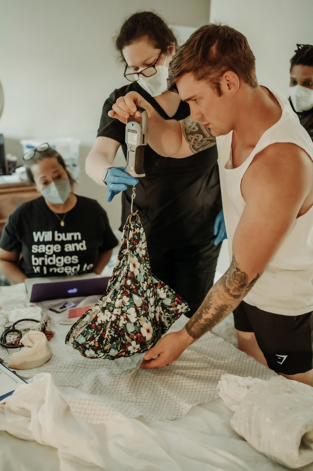 Dad weighing newborn baby with midwife standing nearby