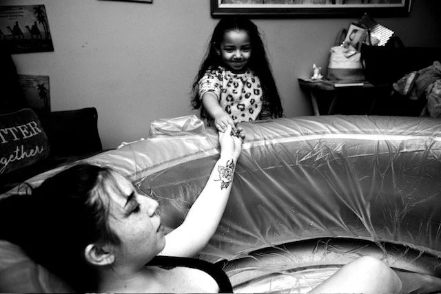 woman in birth tub holding daughters hand