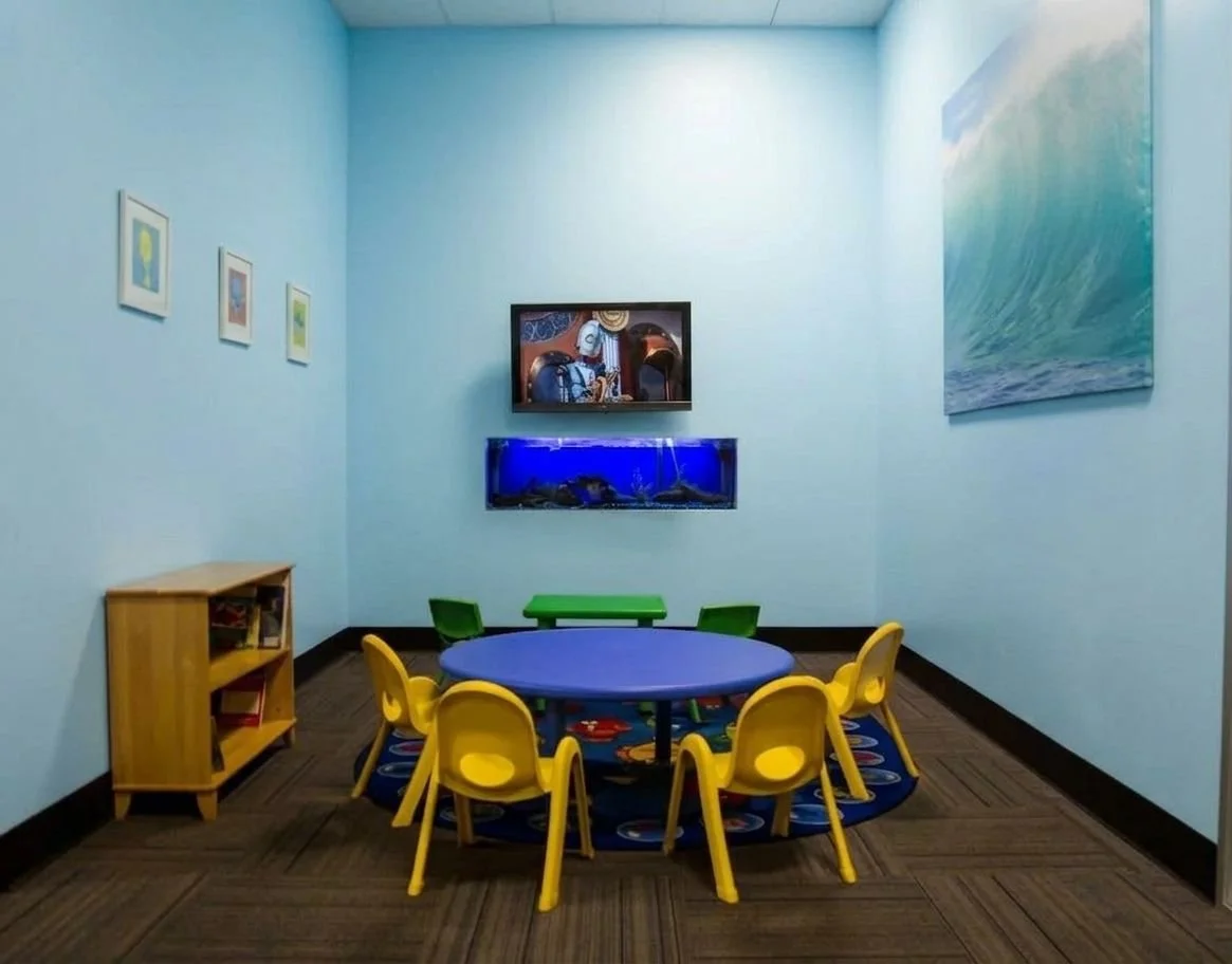 Children's activity waiting room with seating, toys and movies