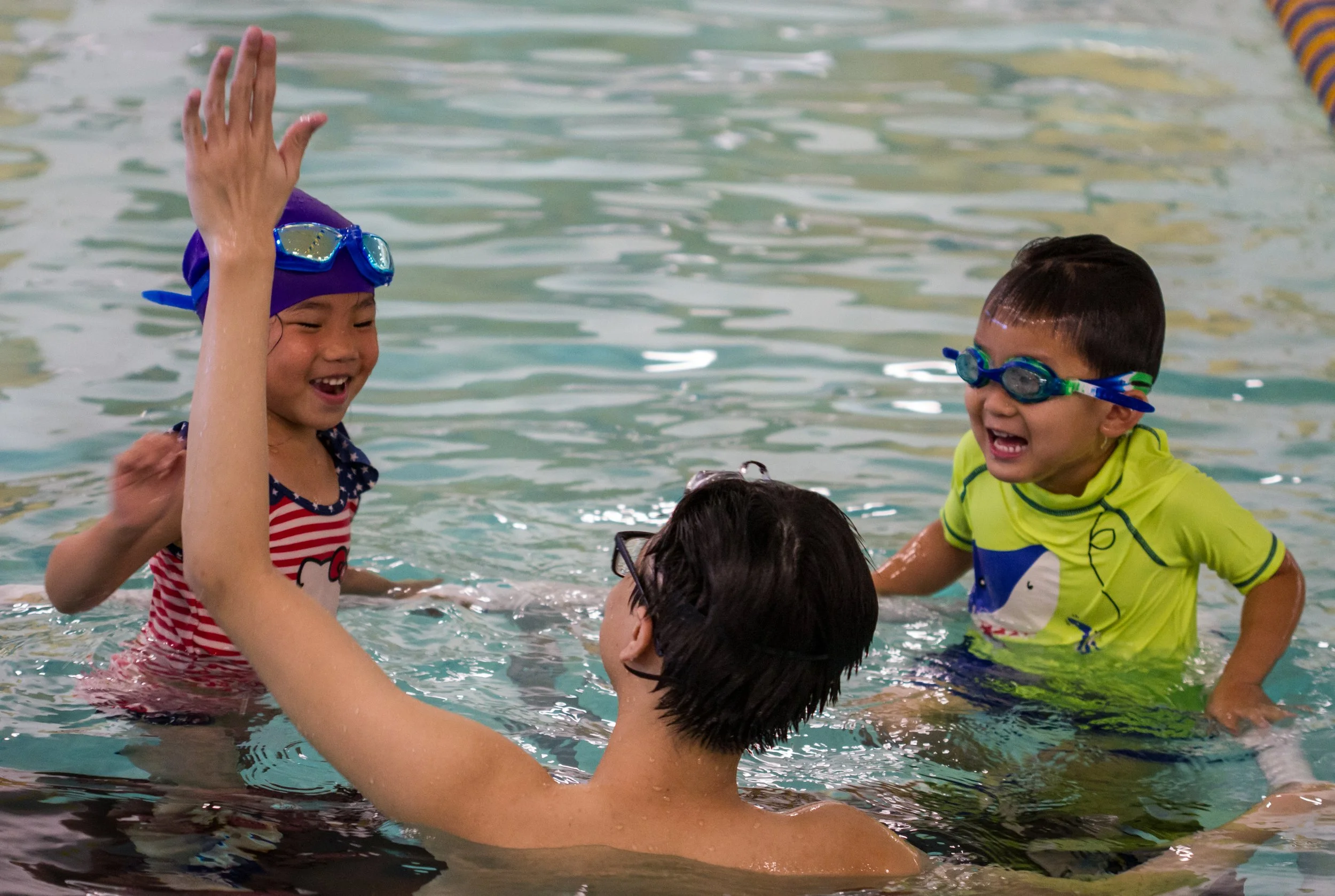 Instructor giving a high five to a young student during swim lessons