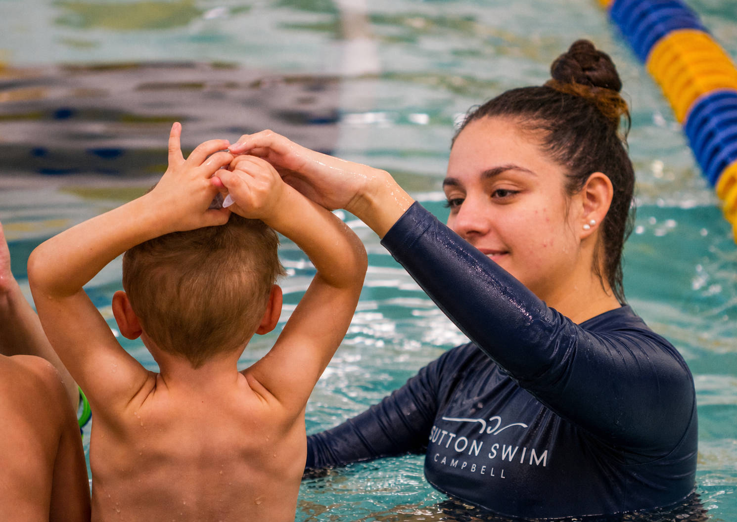 Sutton Swim instructor teaching a young boy proper stroke technique in the pool