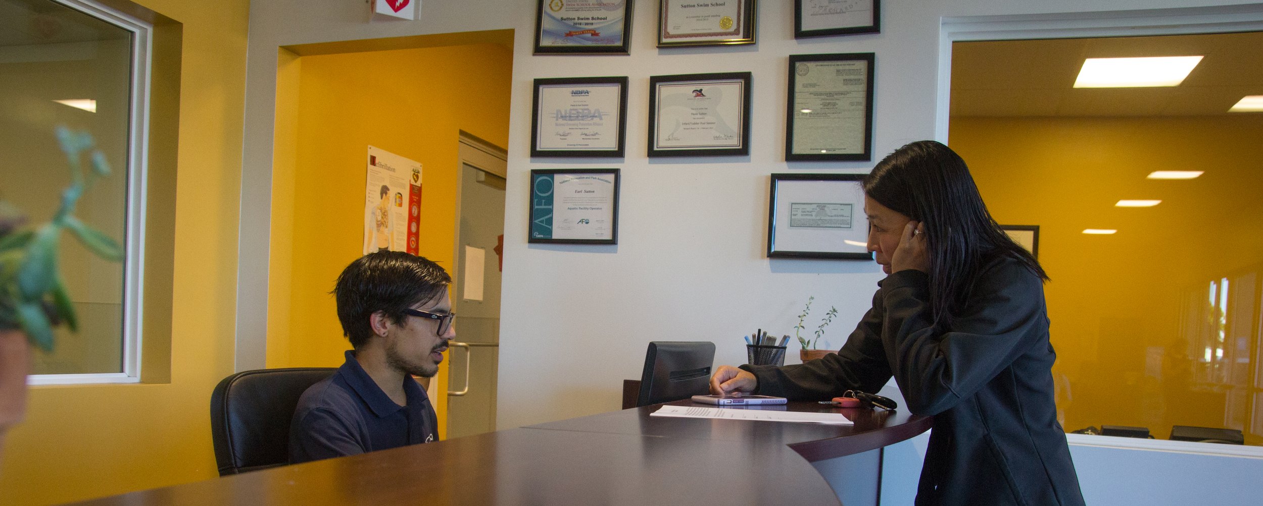 Sales representative assisting a family at the front desk of Sutton Swim School