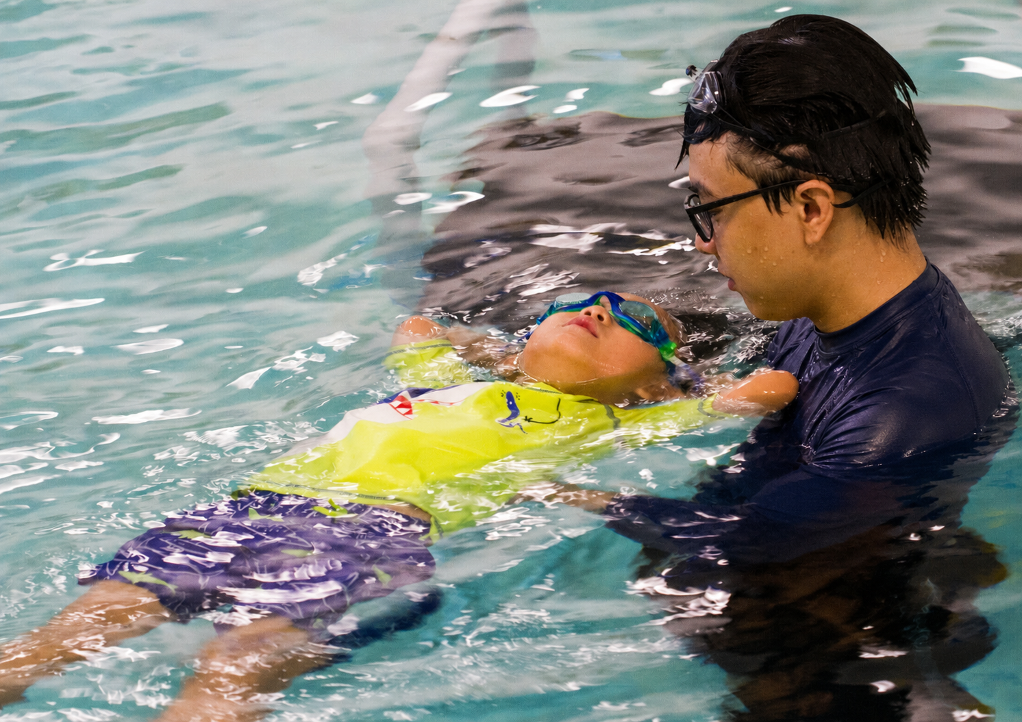 Instructor teaching a young child to swim independently in a heated indoor pool in the South Bay Area