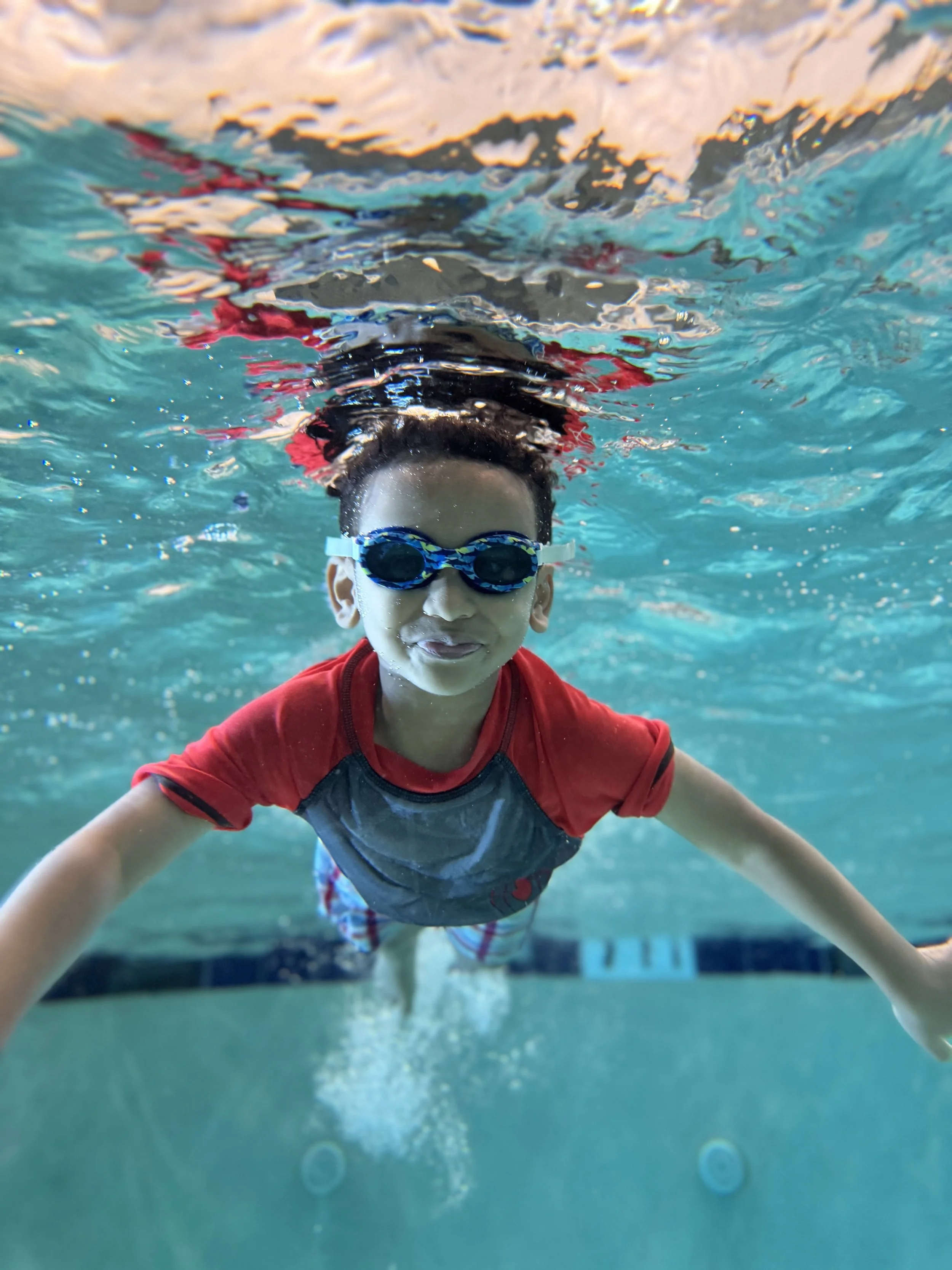 Confident young swimmer gliding underwater with goggles at Sutton Swim School
