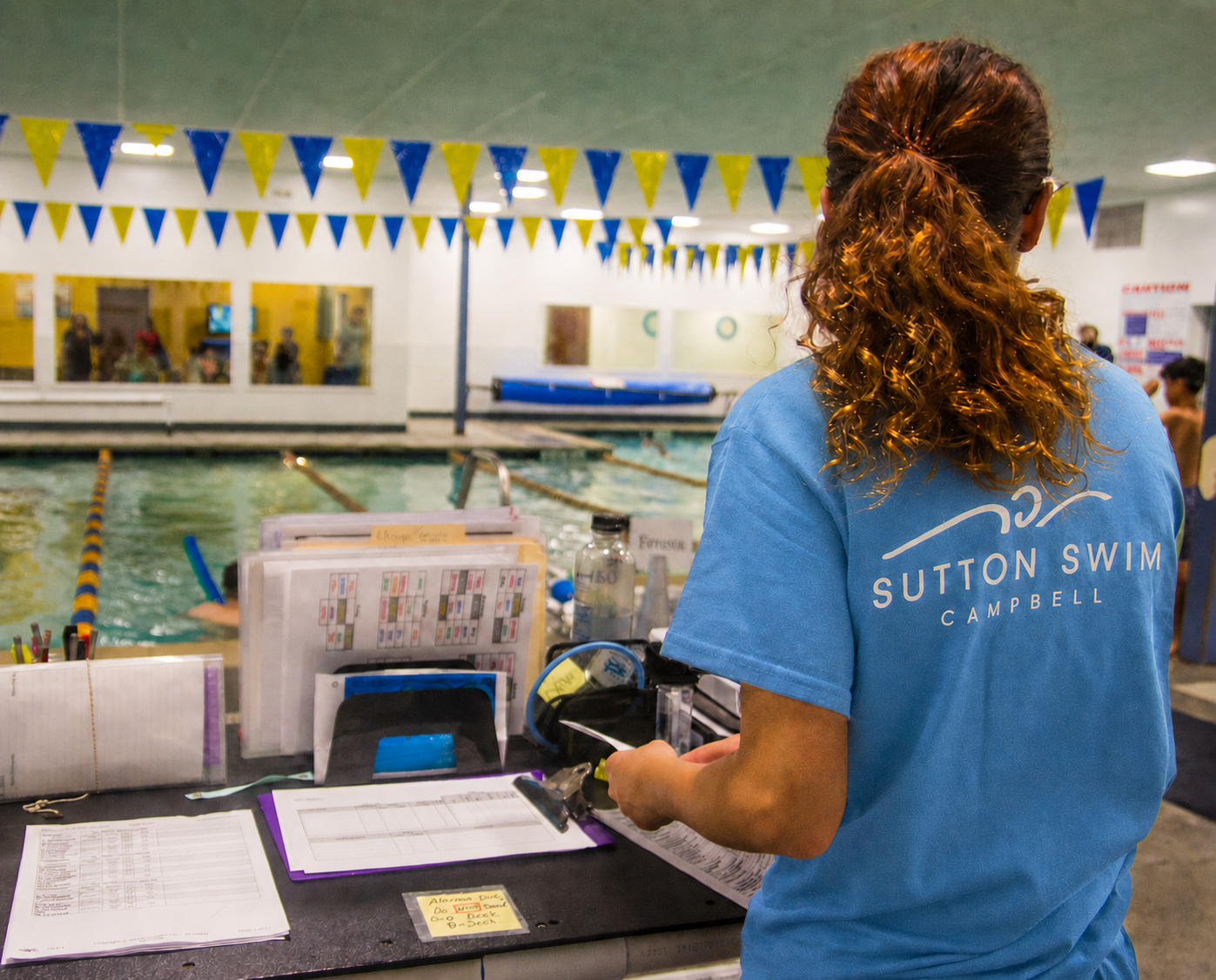 Deck staff member watching swimmers safety poolside at the Bay Area, CA facility