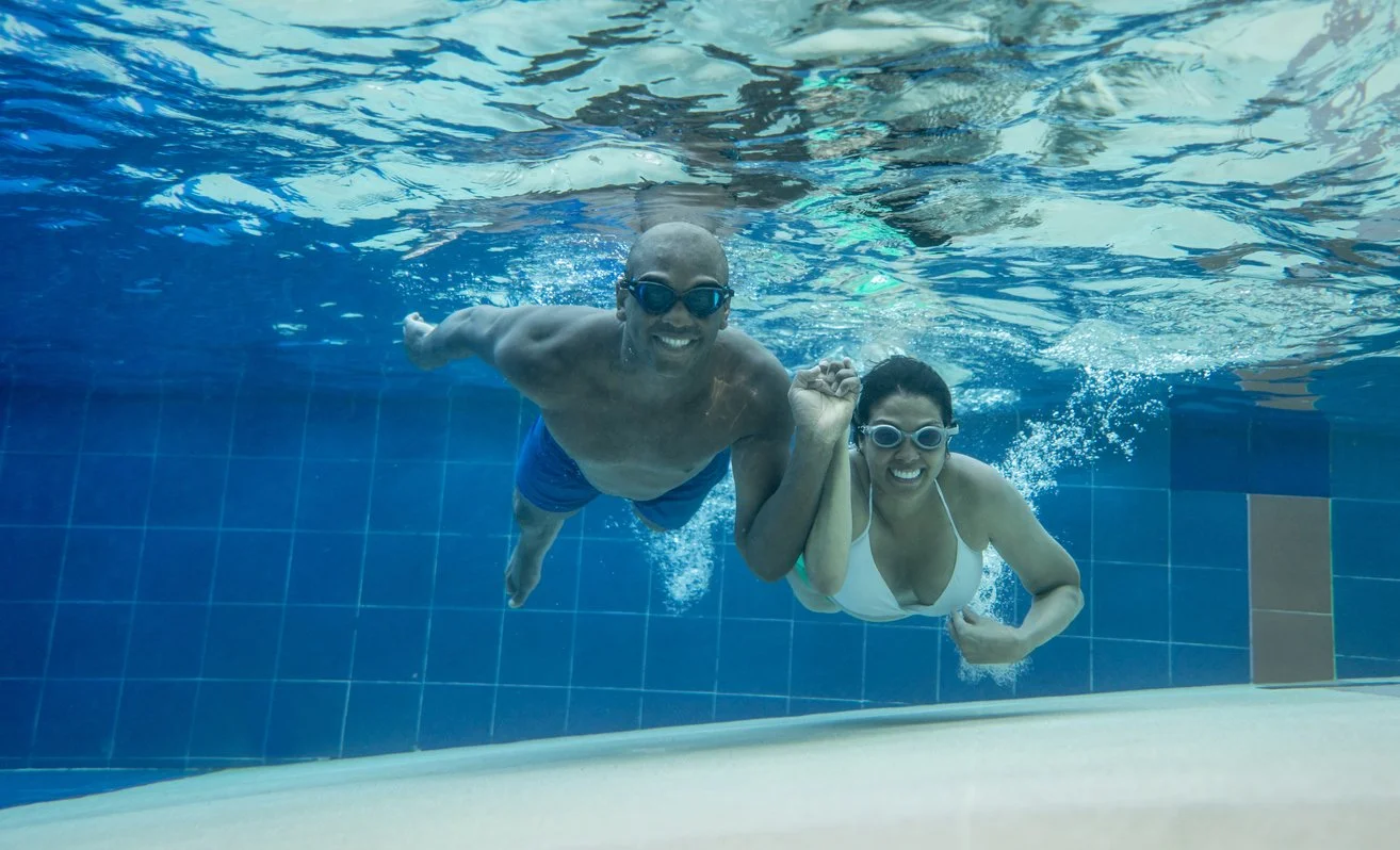 Adults swimming underwater together during adult swim lessons at Sutton Swim School