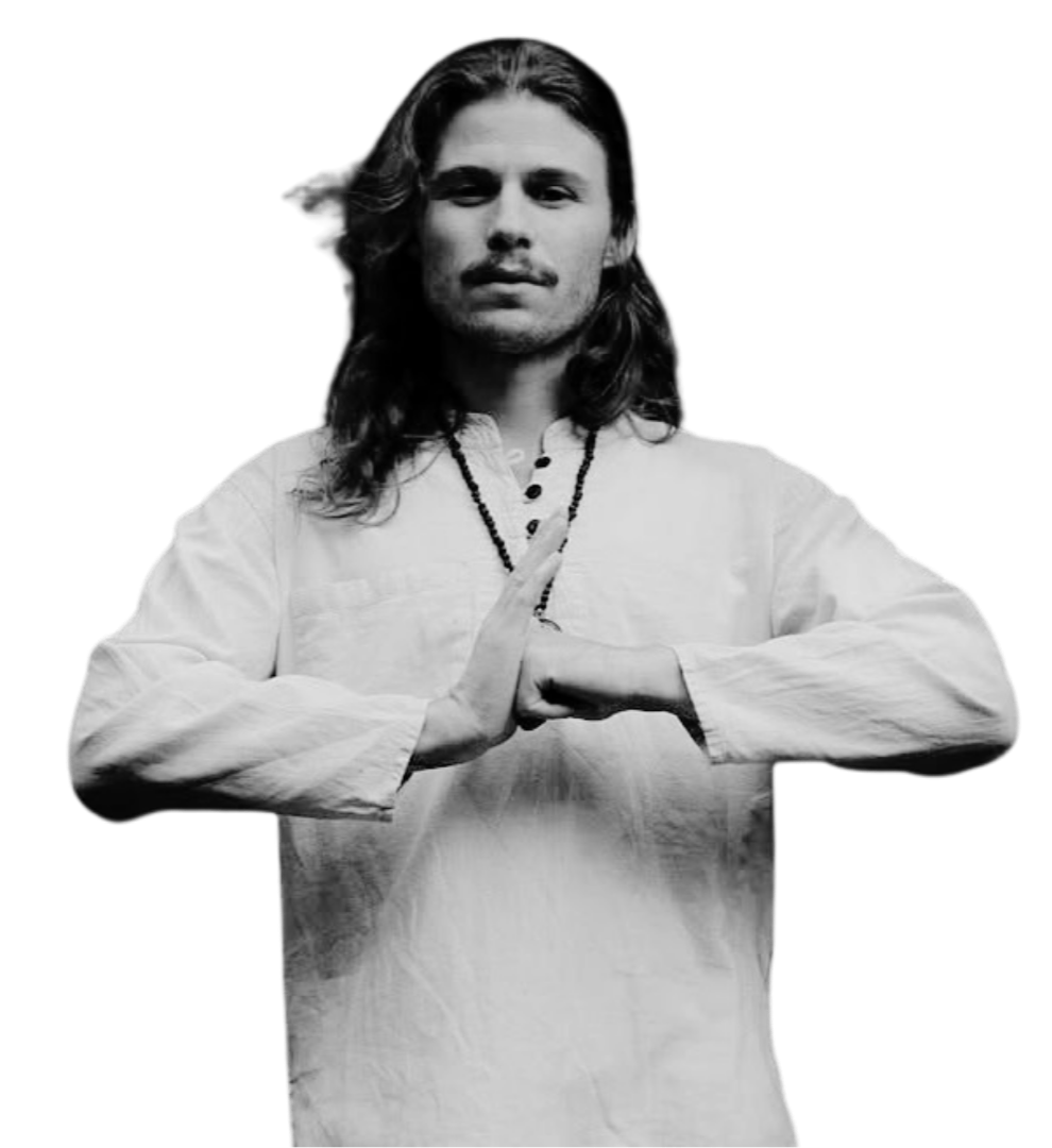 A man with long hair and a beard in a meditative pose, wearing traditional white clothing and a beaded necklace, against a plain background.