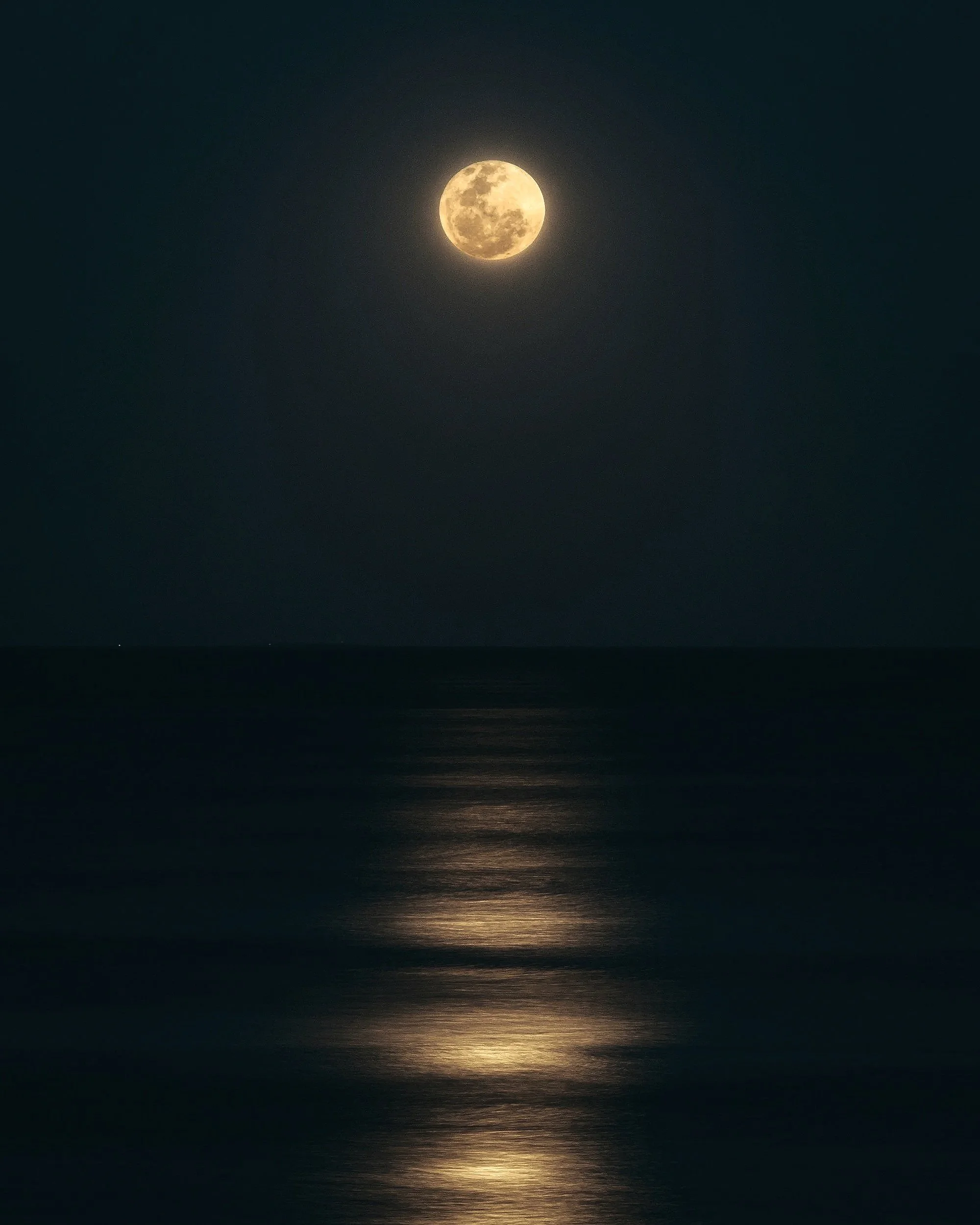 Full moon illuminating the night sky over a calm ocean
