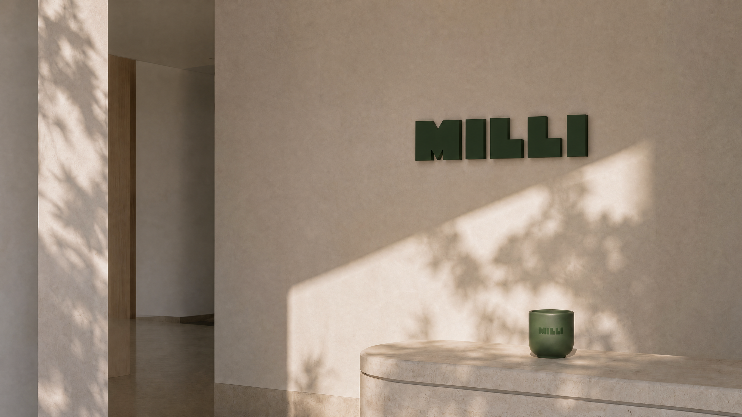 Interior space with a beige wall featuring green 3D letters spelling 'MILLI', a light-colored round table with a green mug that has the same spelling, and soft natural lighting with shadows of leaves.