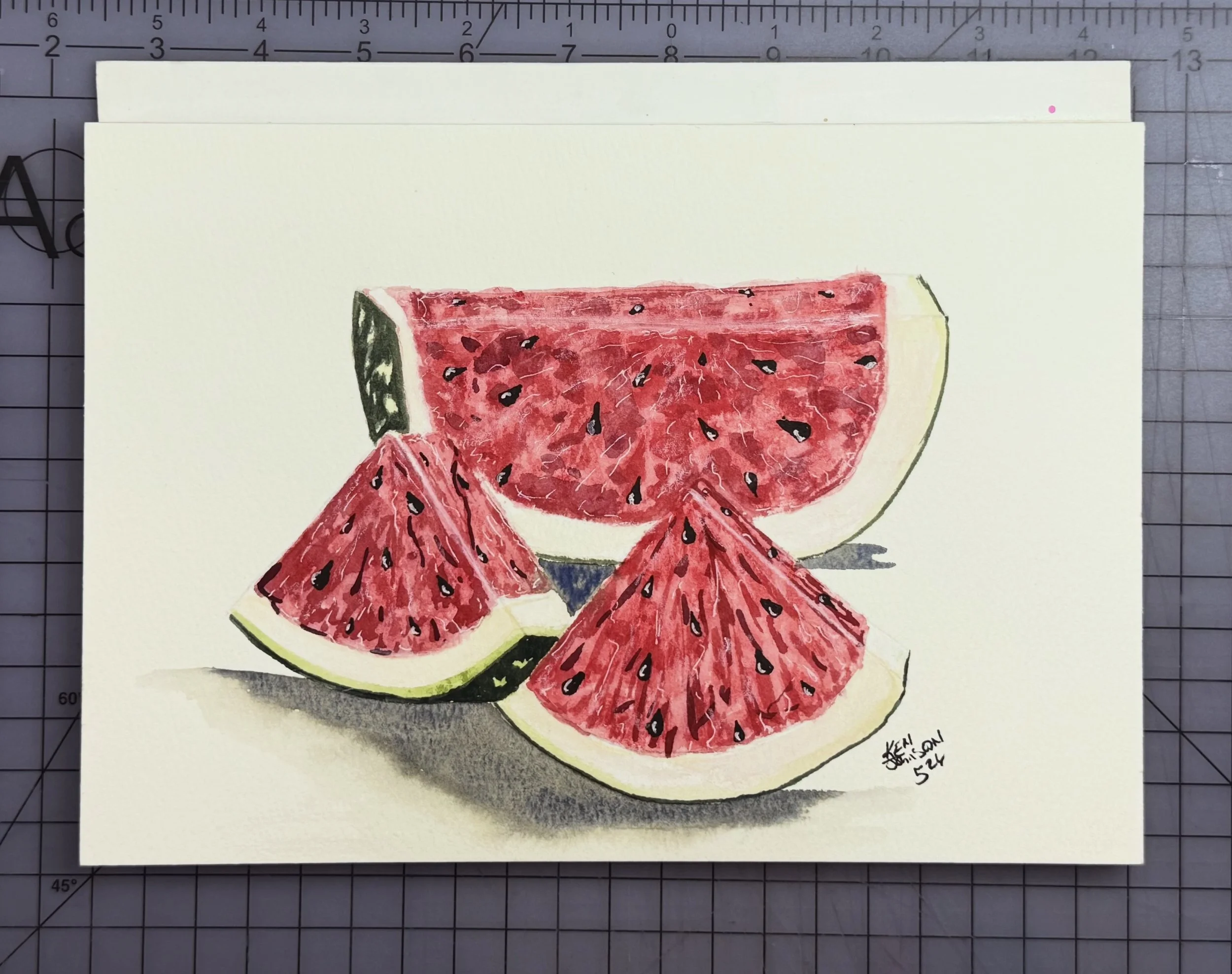 Hand-drawn illustration of a watermelon slice with red flesh, black seeds, and a green rind. The drawing is on a piece of paper with a grid background.