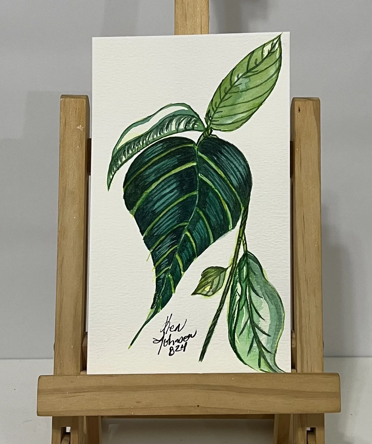 Watercolor painting of green leaves on a white background with a signature and date at the bottom.