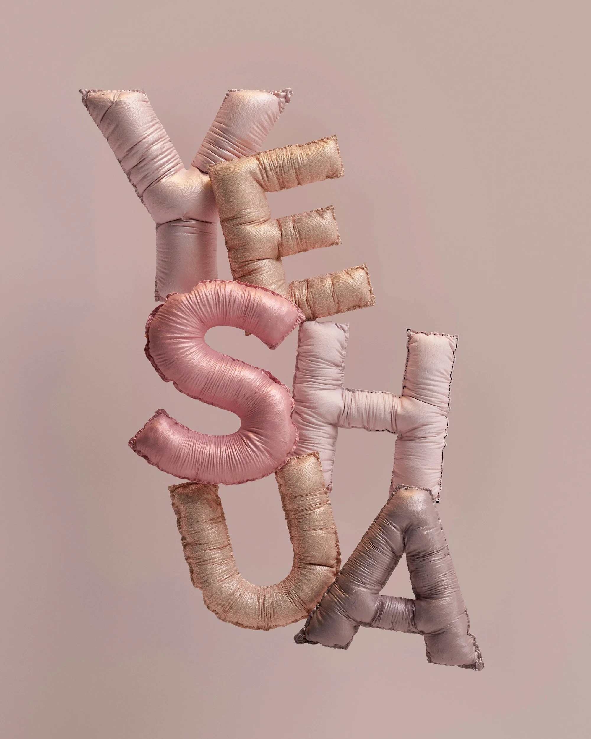 Pink, rose gold, and metallic colored balloon letters spelling out the word 'YES' against a light pink background.