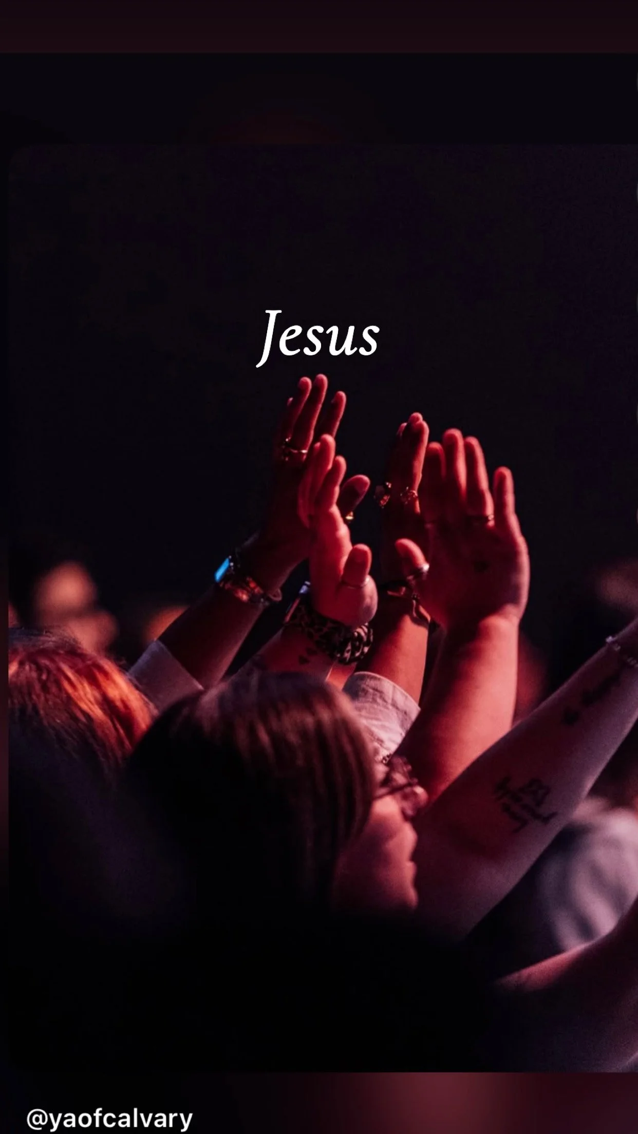 People raising their hands in worship during a religious service, with the word 'Jesus' written in the center of the image.